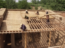 Villagers use simple tools and natural materials to build the school