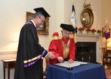 Professor Levin (right) signs on the Register of Honorary Graduates.