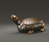 Gilt Silver Case in the Shape of a Tortoise
Tang dynasty, 618–907
Height 13 cm, length 28.3 cm, width 15 cm, weight 820.5 g
Unearthed from the back chamber of the underground palace of Famensi pagoda in Fufeng county in 1987

This object is an offering made by Emperor Xizong and is simply referred to as the “tortoise” in Yiwuzhang（the inventory）. Some believe it is a container for tea powders. However, the hole at the mouth of the tortoise suggests it is probably an incense burner. The image of smoke coming out of the mouth of a tortoise is found on a incense burner also unearthed from Famensi. In 1990, a tortoise case was found among the Tang-dynasty silver hoard in Fanzhi county, Shanxi province, which probably has a similar function. The body of the tortoise is hammered and connected to the head and tail by welding.