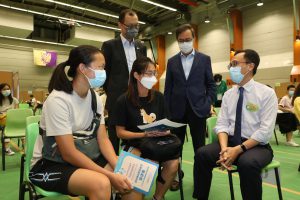 Mr. Patrick Nip, Professor Alan Chan and Mr. Eric Ng communicate with CUHK members participating in the outreach vaccination service.